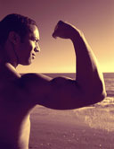 Image Man flexing arm with the ocean in the background