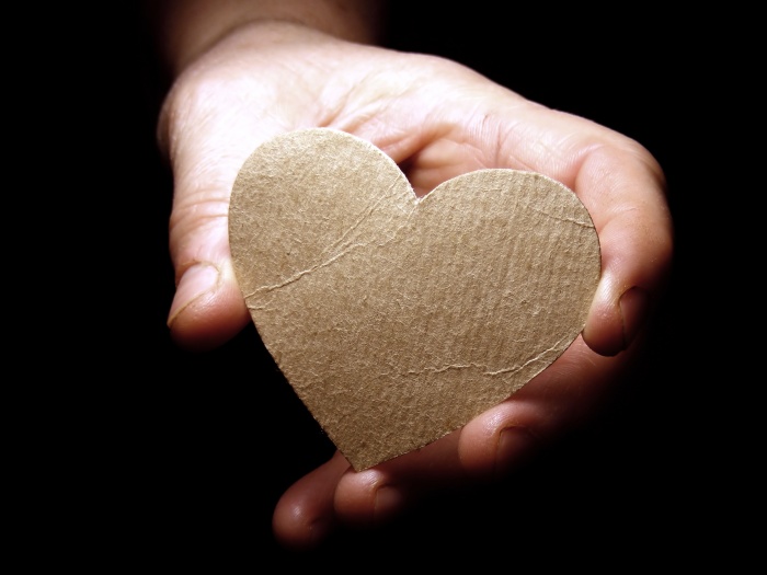person holding cardboard heart for torture survivors stories