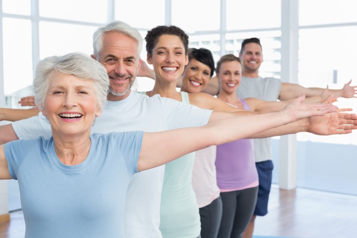 Portrait of fitness class stretching hands in row practicing yoga and mindfulness