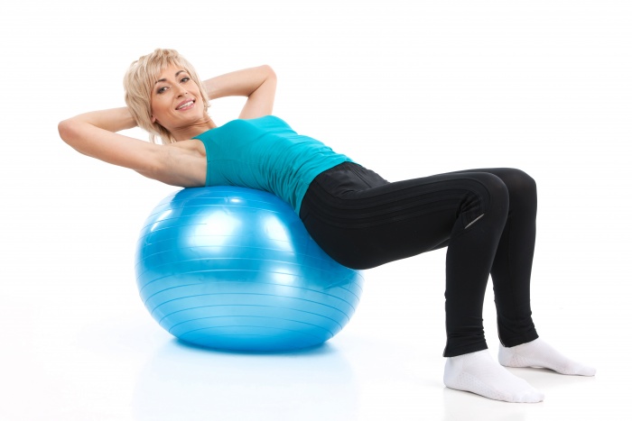 aged lady lying on fitness ball. blond woman workout on white background