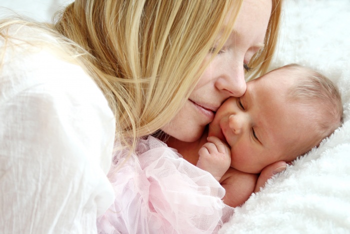 young mother snuggling newborn infant showing reduced signs of postpartum anxiety