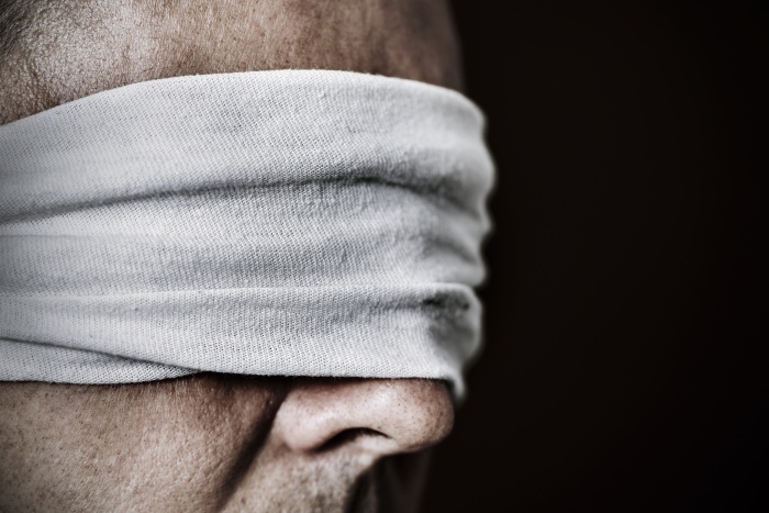 closeup of a young man with a blindfold in his eyes, as a symbol of oppression or repression
