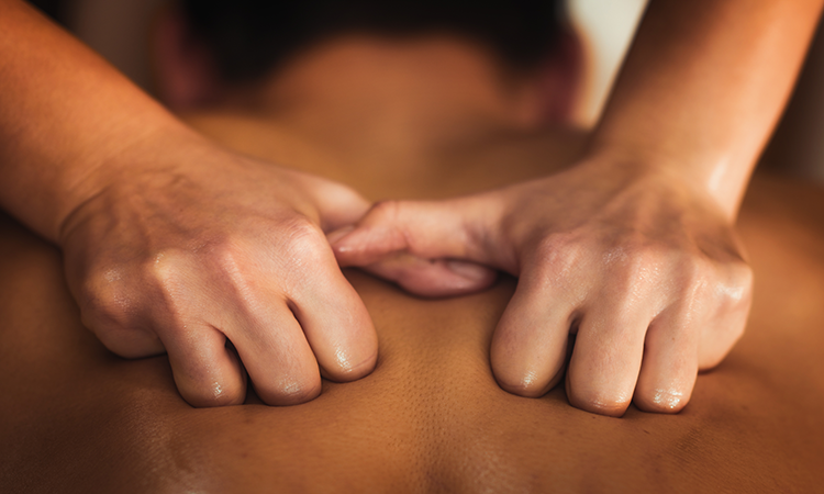 A massage therapist massages a client's back.