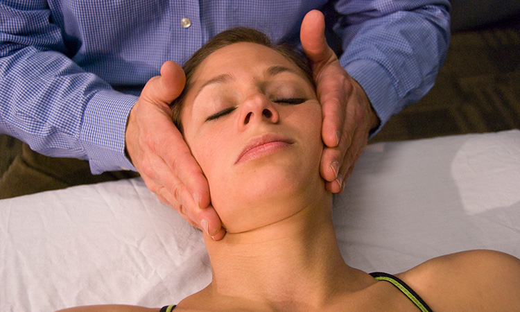 An image of a woman receiving massage therapy to her neck is used to illustrate the concept of cranial positional release therapy.