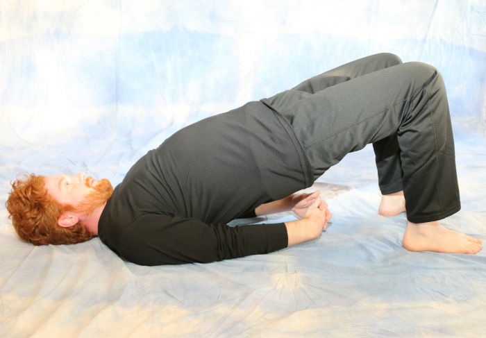 male yoga practitioner doing bridge pose