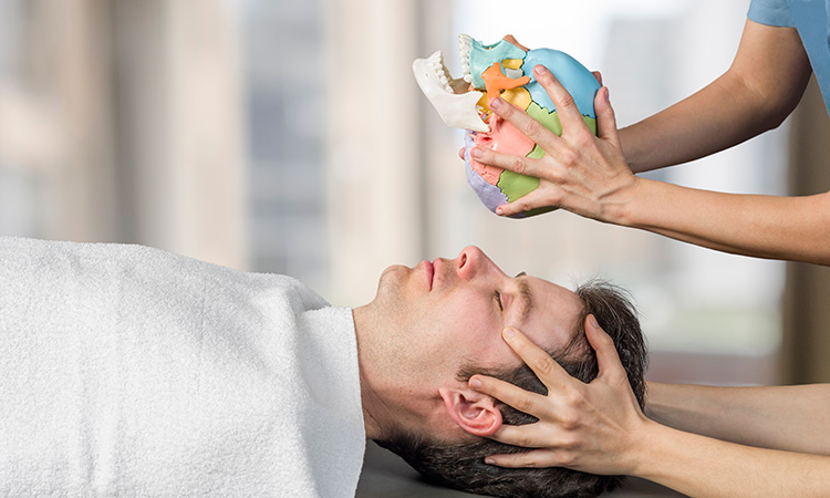 An image of a person having his forehead and temples massaged is used to illustrate the concept of craniosacral therapy.
