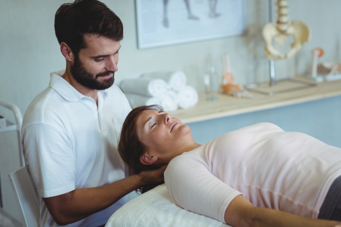 Physiotherapist giving neck massage to a woman
