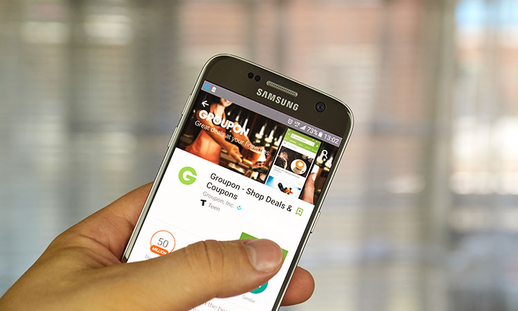 An image of a person's smartphone with the the Groupon website showing up on it is used to illustrate the concept of understanding how Groupon works for business.