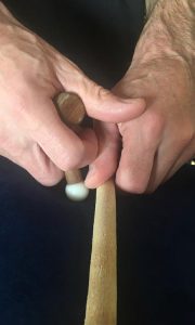 In this picture, the dowel represents spinous processes. Keep your thumb next to the spinous processes to ensure that you don't press into them with the massage tool.