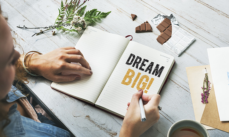 A photo of a person writing the words "dream big" in a journal is used to illustrate the concept of increasing your income.