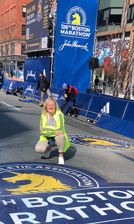 Mary White kneels at the finish line of the 2022 Boston Marathon.