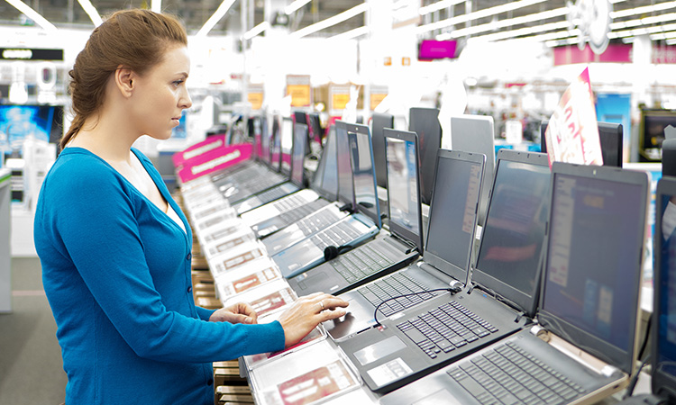 An employee works on a workplace laptop computer, to illustrate the concept of computer literacy and knowledge that is now necessary to being a massage therapist.