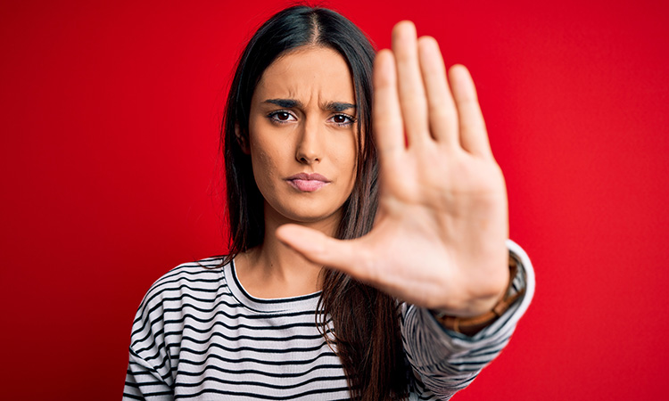 A woman holds her hand up in front of her, palm out, in a gesture of "stop!" to illustrate the concept of protecting one's personal safety.
