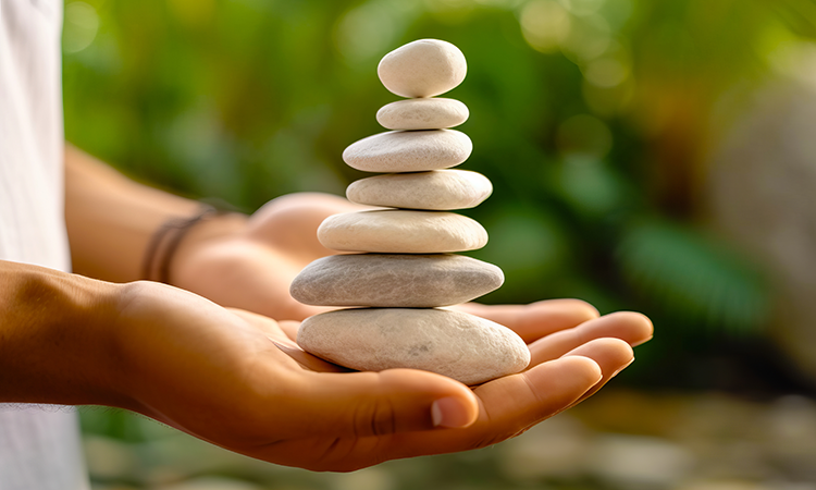 An image of hands holding a stack of smooth spa stones is used to illustrate the concept of investing in a spa-related small business.