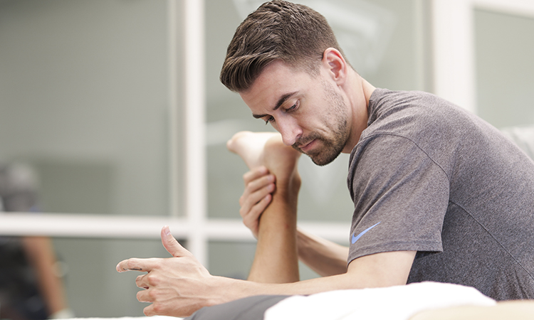 Tennessee Titans massage therapist Blake Mundell works on an NFL athlete, an example of massage therapy for athletes.