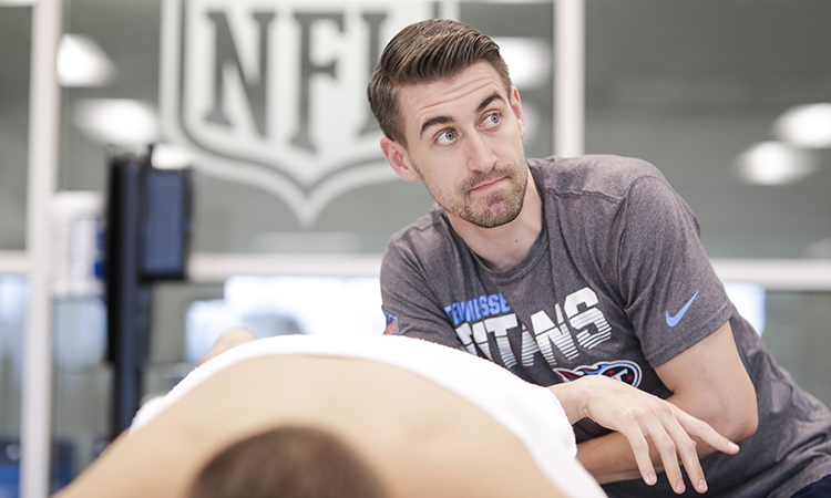Tennessee Titans massage therapist Blake Mundell works on a team player, an example of massage therapy for athletes.