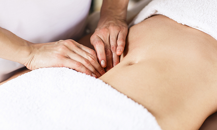 Woman having visceral manipulation, the therapist's hands pushing into her abdomen.