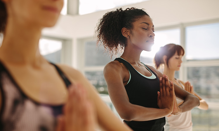 An image of women practicing yoga is used to illustrate the concept of the benefits of regular yoga practice.
