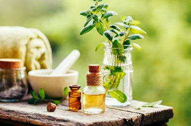 Spa still life with essential oil, fresh peppermint and towel on wooden background outdoors.
