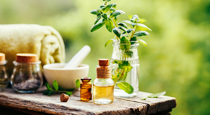 Spa still life with essential oil, fresh peppermint and towel on wooden background outdoors.