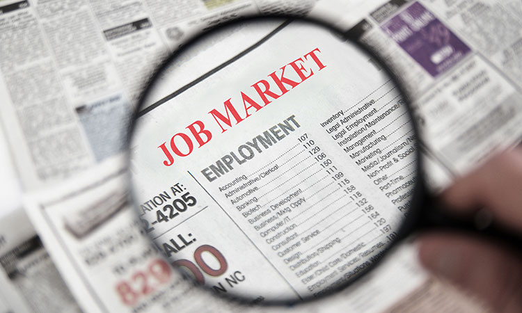 A magnifying glass shows text in a newspaper that reads Job Market Employment