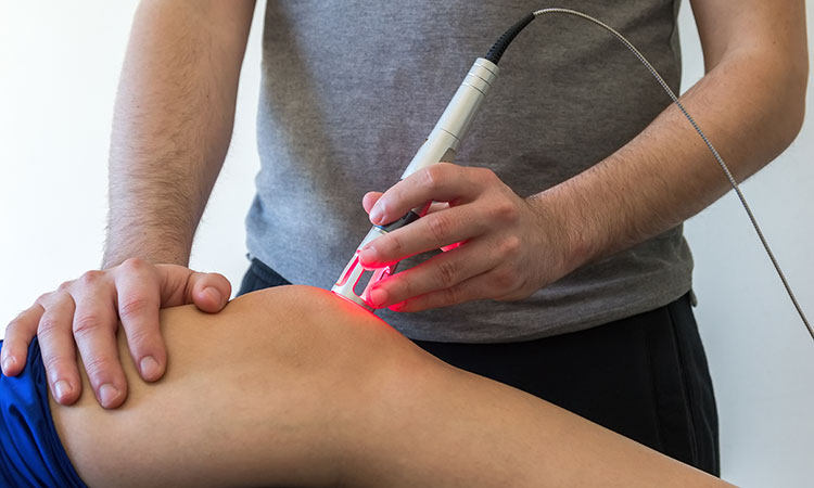 An image of a therapist using a handheld laser on a client is used to illustrate the concept of laser therapy.