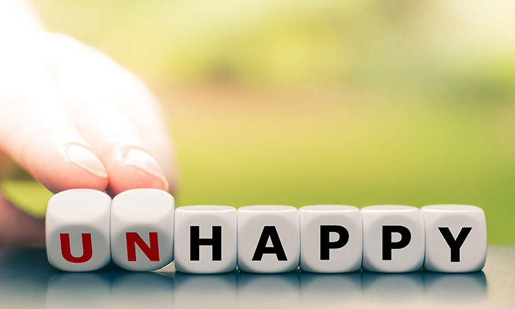 Wooden blocks that spell out "unhappy" are used to illustrate the concept of noticing moments of happiness.
