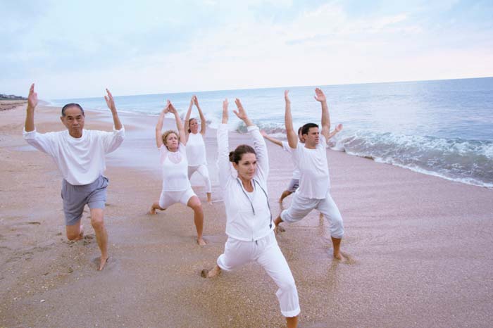 people practicing yoga on beach